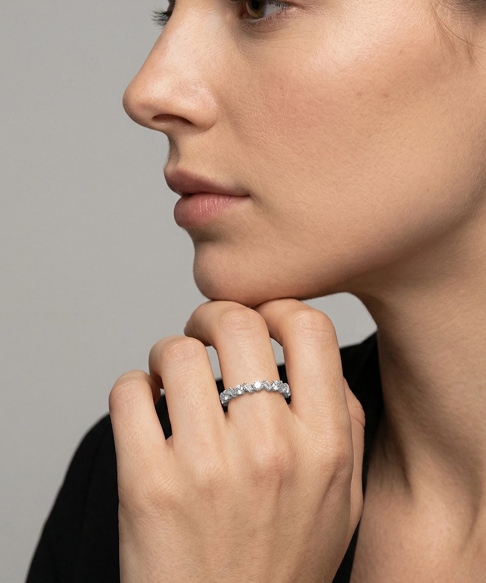 Close-up of a woman's hand wearing a diamond ring against a neutral background