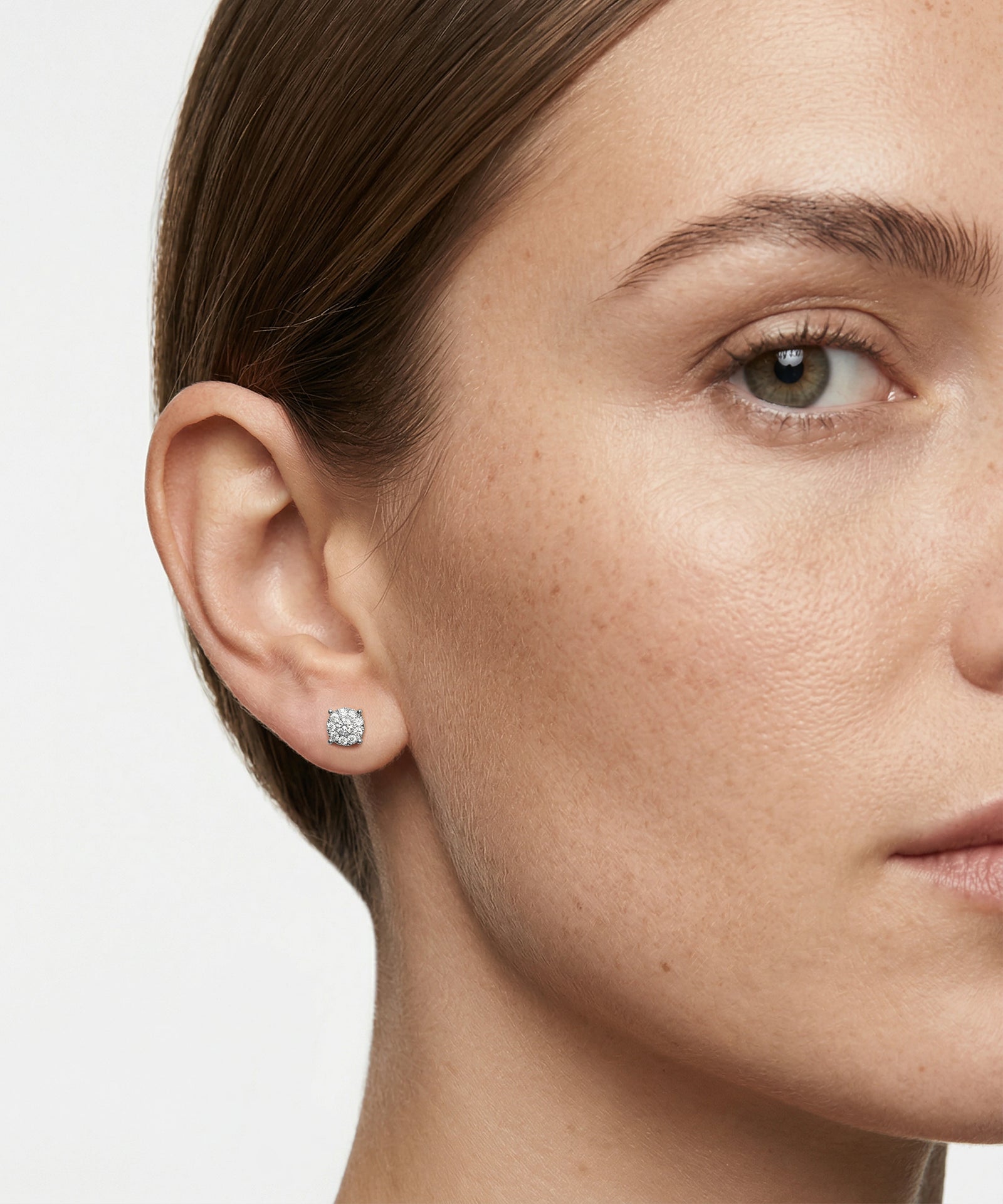 Close-up of a woman wearing diamond earrings with a neutral background