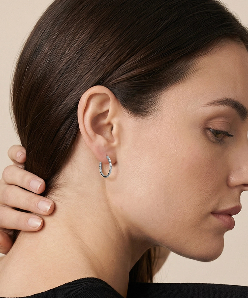 Close-up of a woman wearing a gold hoop earring against a neutral background