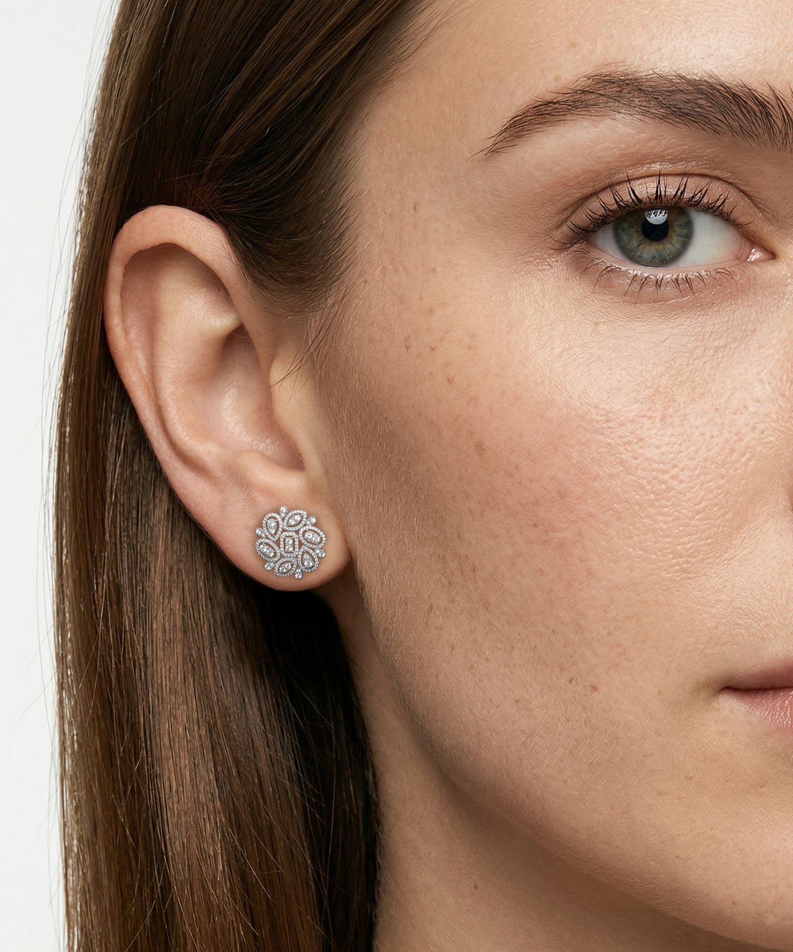 Close-up of a woman wearing diamond earrings with a neutral background