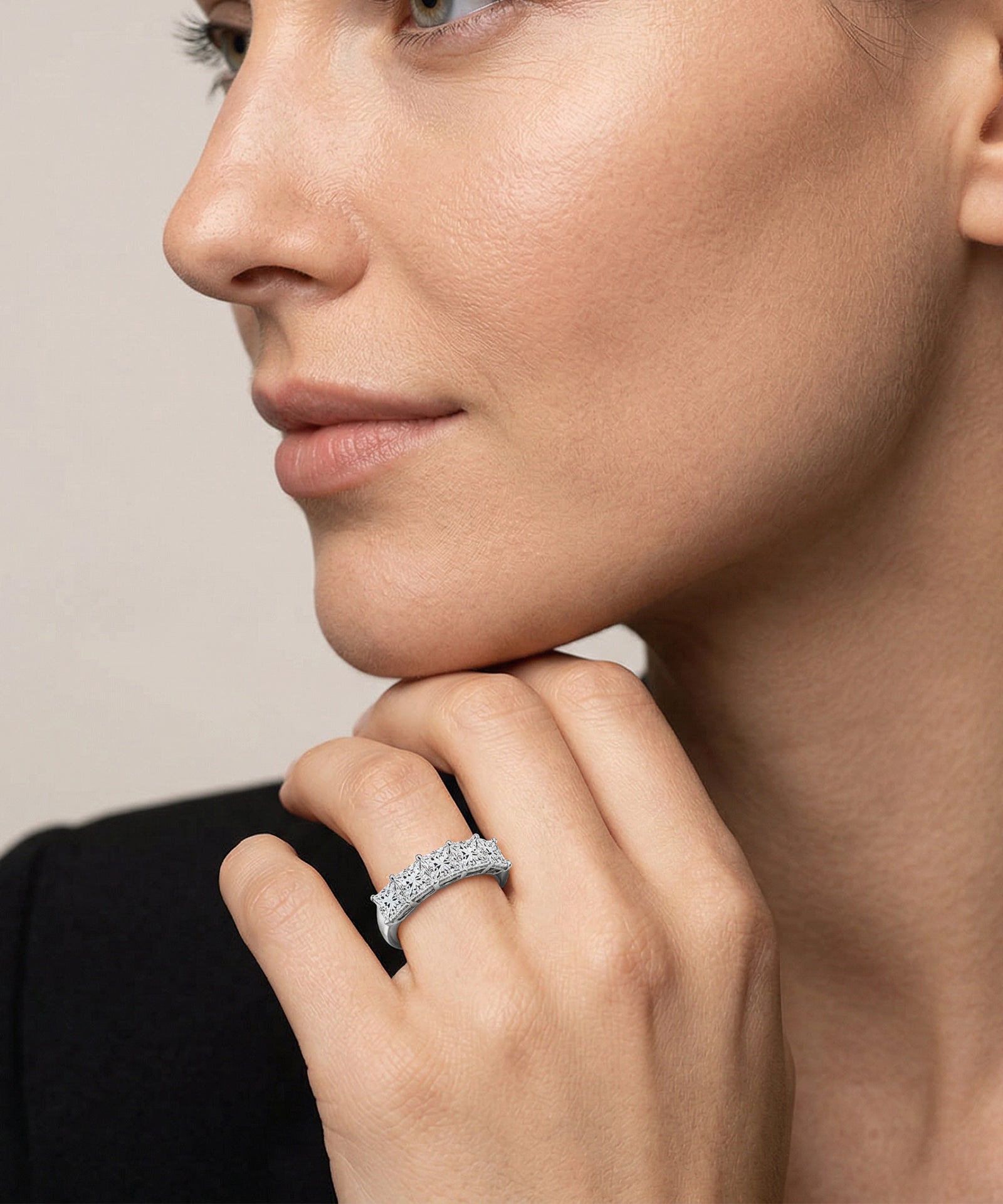 Close-up of a woman wearing a silver ring on her finger against a neutral background