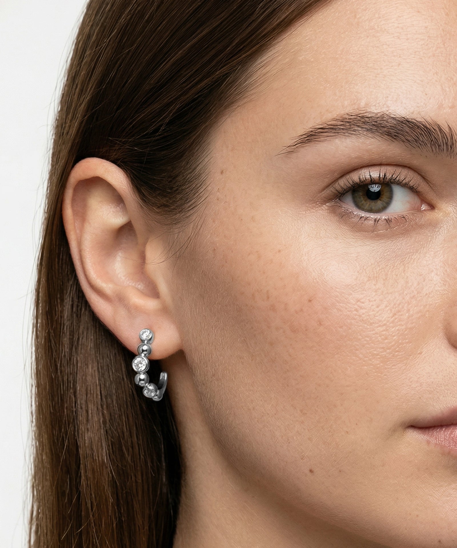 Close-up of a woman wearing a silver earring with a white background