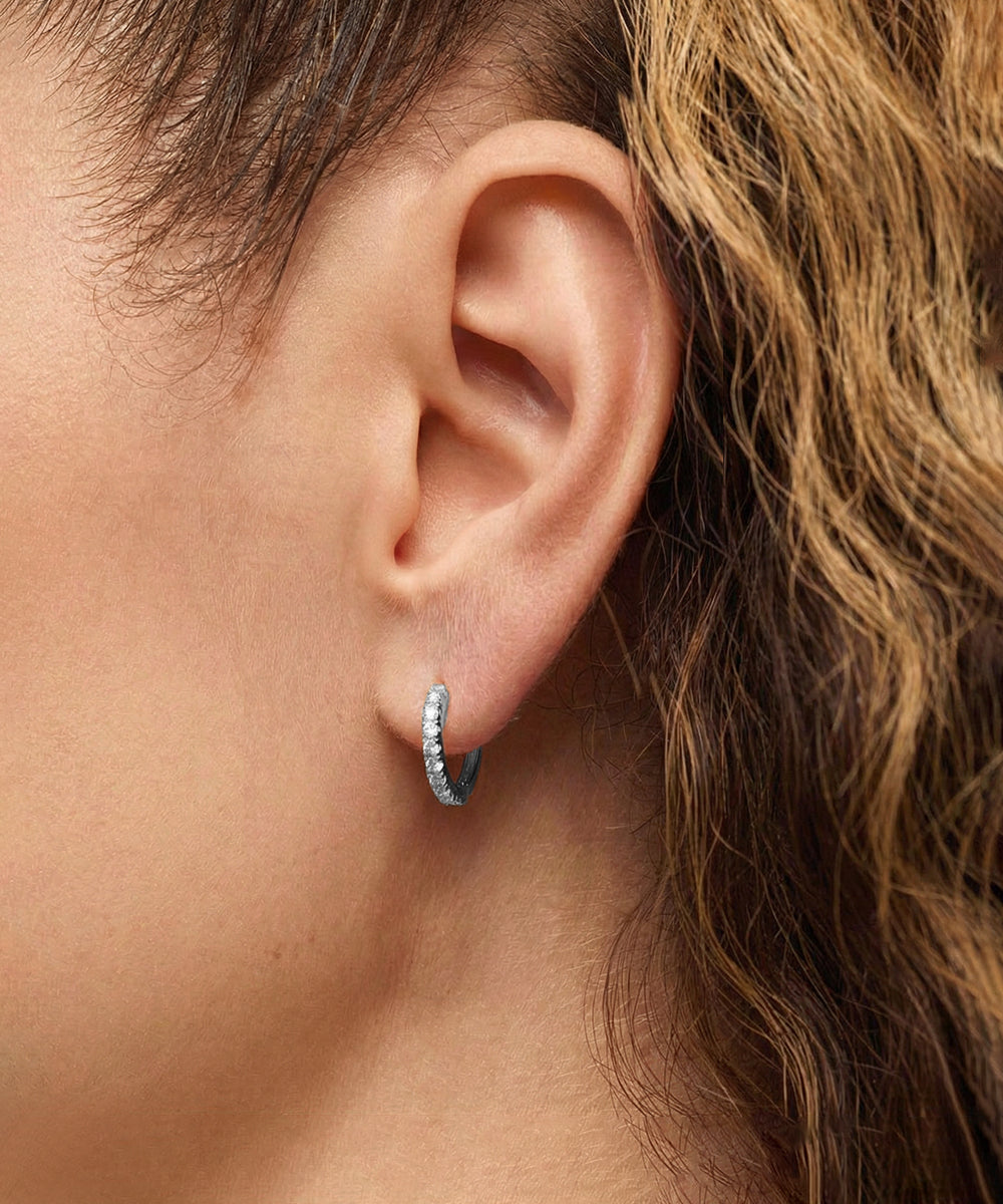 Close-up of an ear wearing a small hoop earring with a blurred background