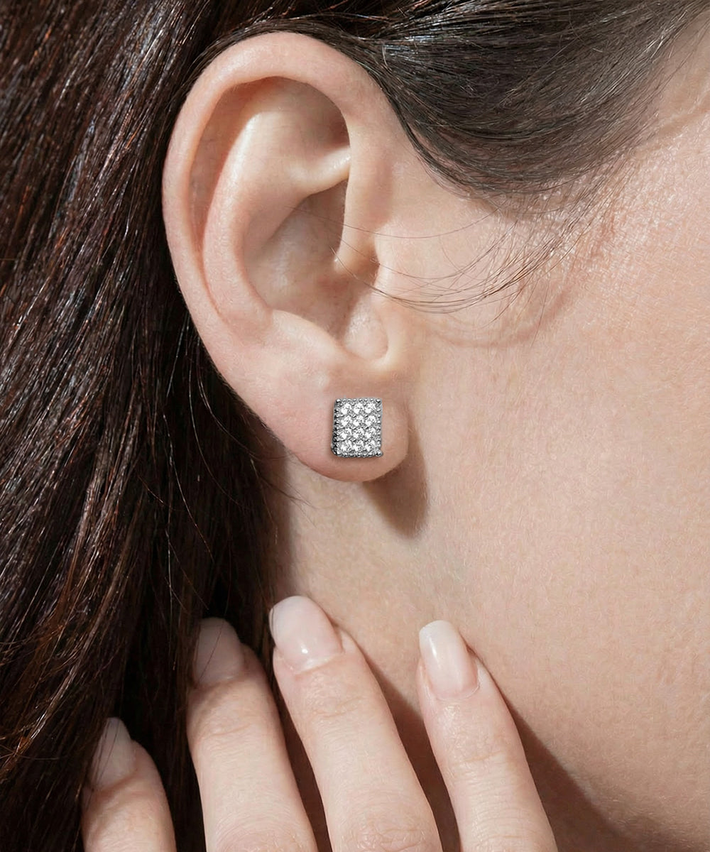 Close-up of an ear wearing a diamond stud earring with a hand touching the cheek.