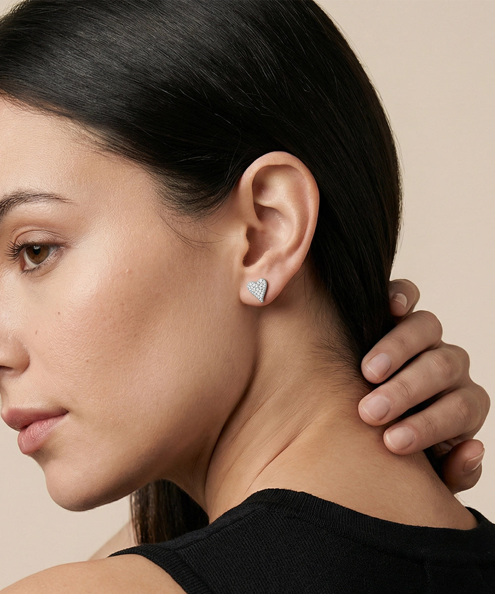 Close-up of a woman wearing a heart-shaped earring with a beige background