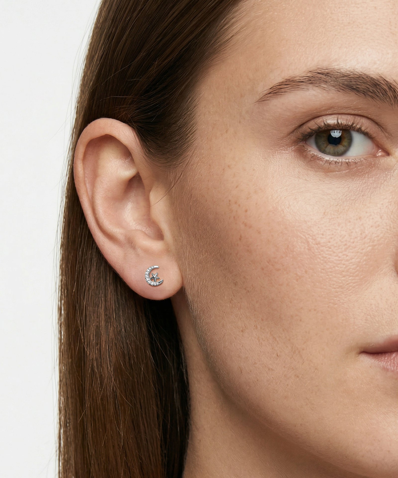 Close-up of a woman wearing a silver earring with a small gemstone.