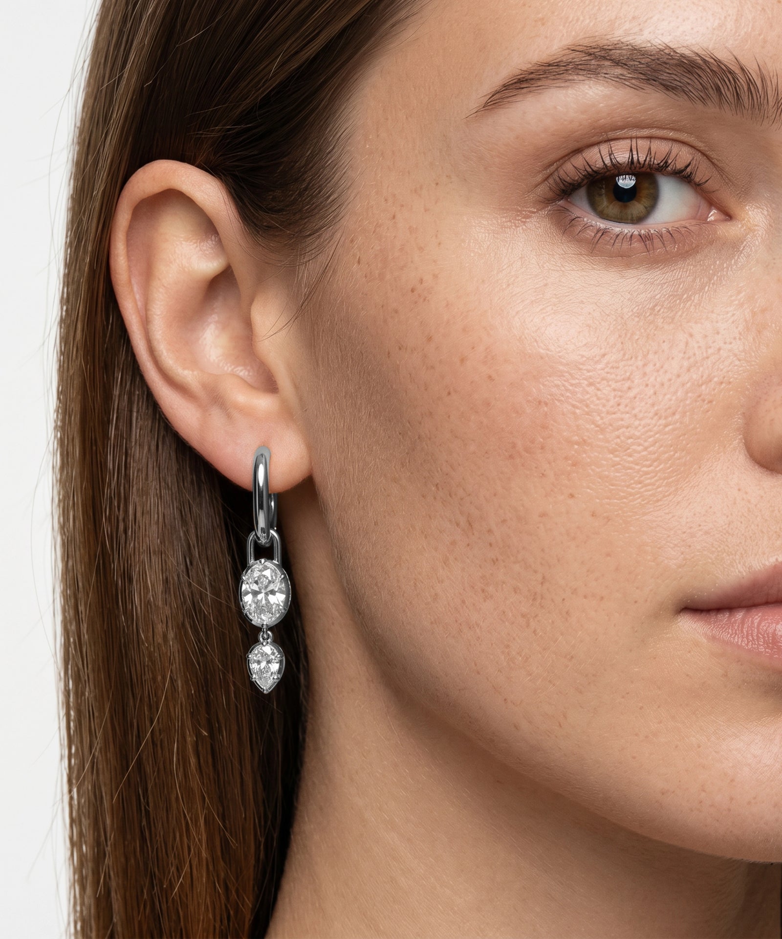 Close-up of a woman wearing silver hoop earrings with clear gemstones.