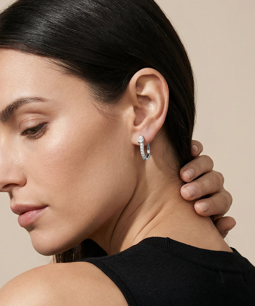 Close-up of a woman wearing gold hoop earrings with a neutral background