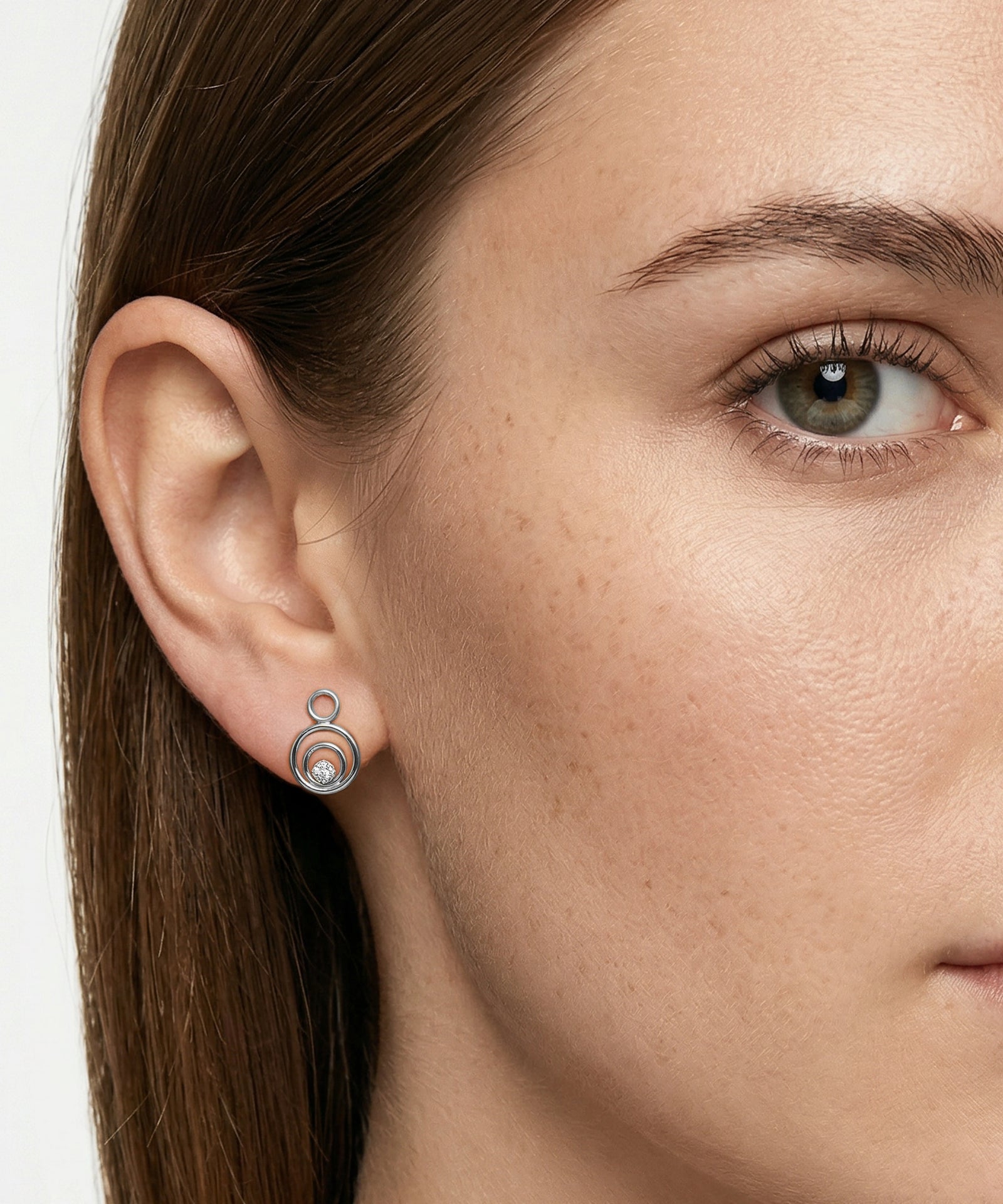 Close-up of a woman wearing a silver earring with a circular design.