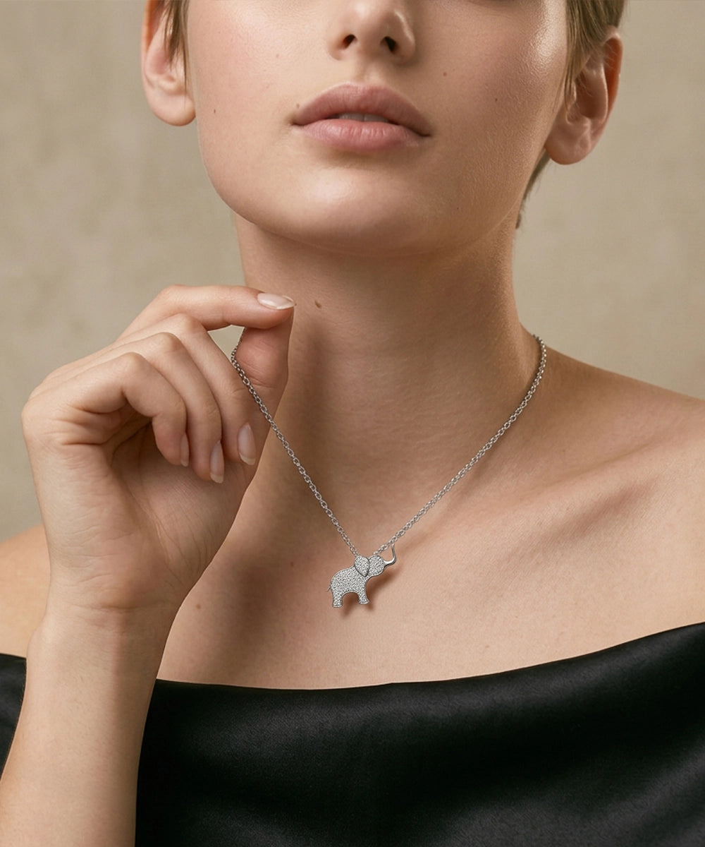 Woman wearing a silver necklace with an elephant pendant against a neutral background
