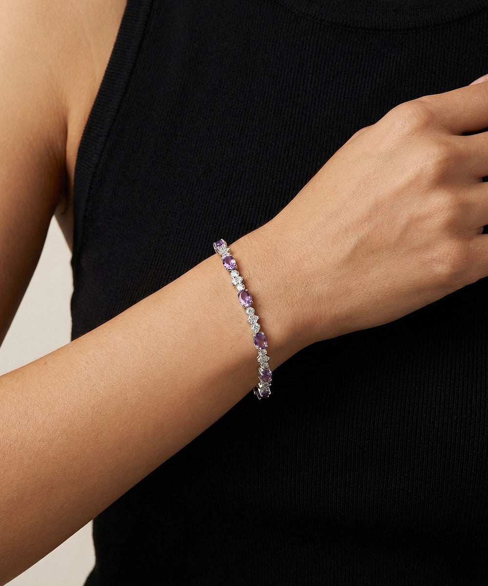 Bracelet with purple stones on a person's wrist against a black background