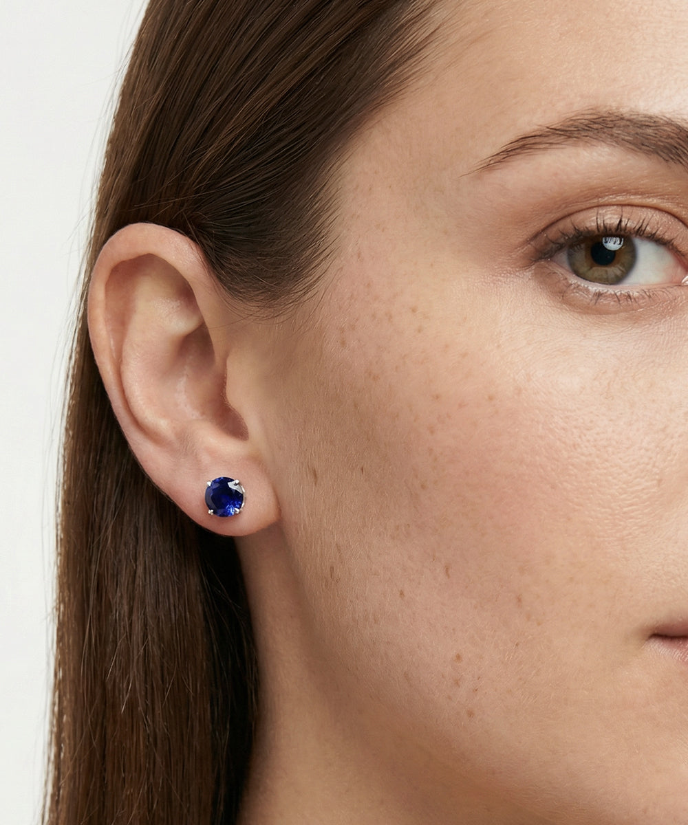 Close-up of a woman wearing a blue gemstone earring.
