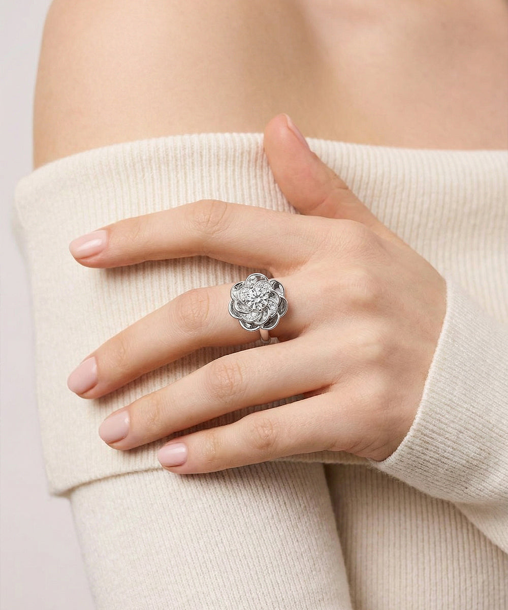 Hand wearing a silver ring with floral design on a light background