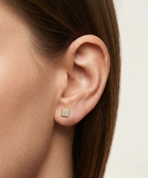 Close-up of an ear wearing a silver earring with a white background
