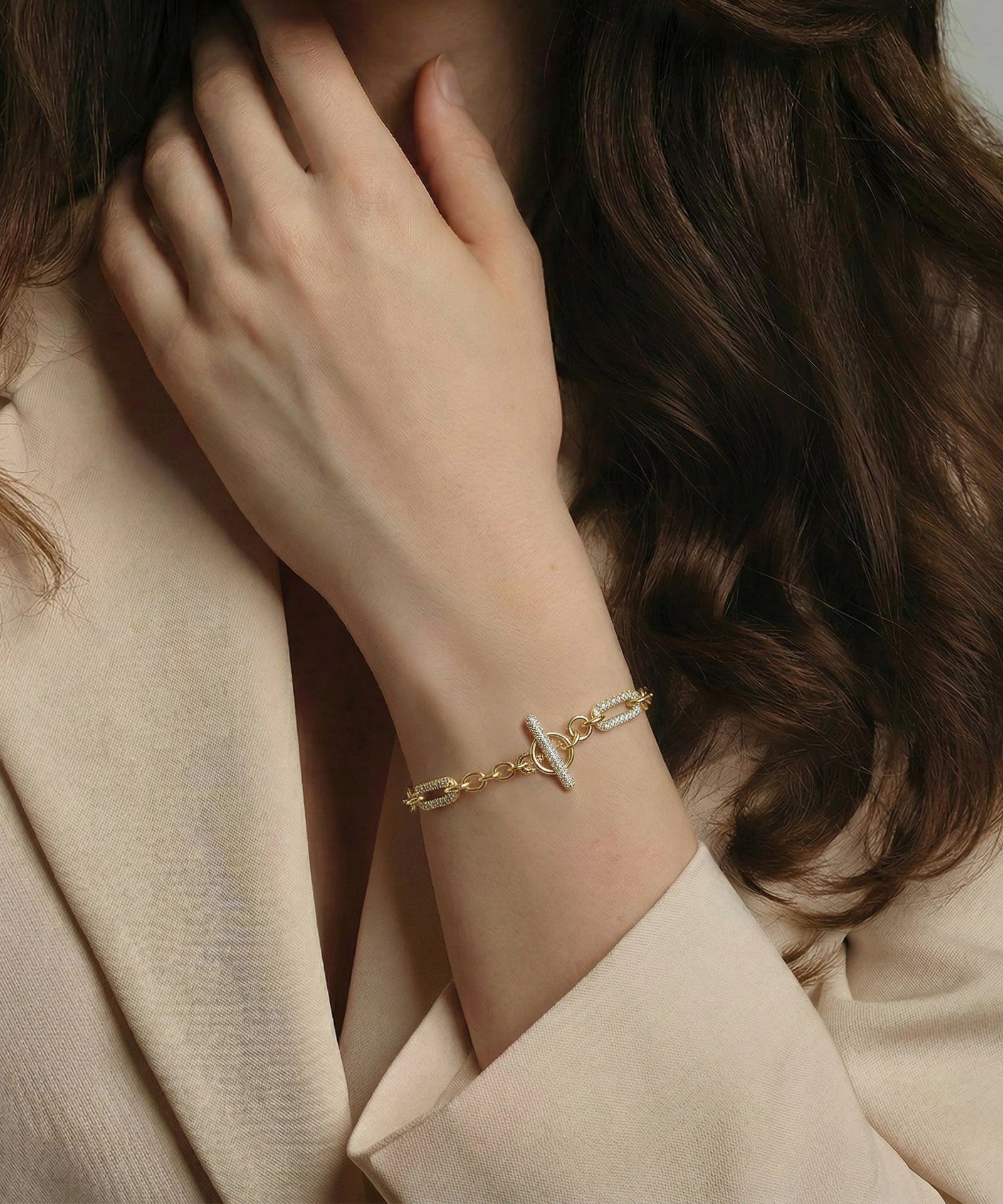 Gold bracelet on a wrist with a neutral background