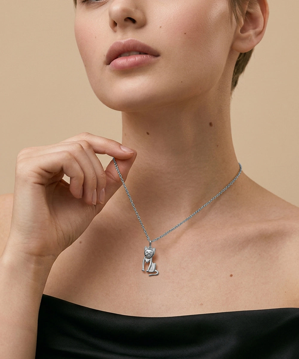 Woman wearing a silver necklace with a cat pendant against a beige background