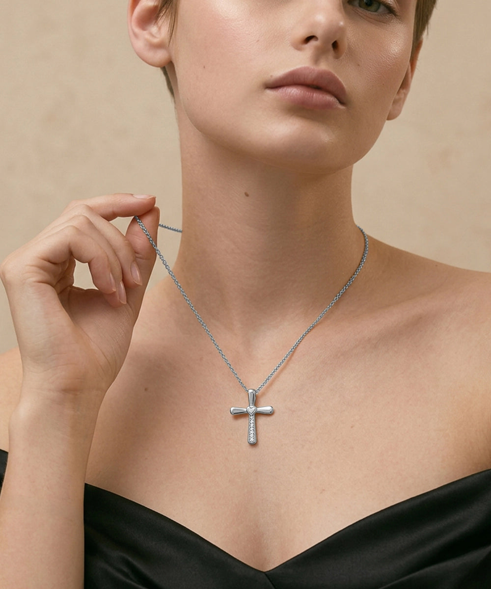 Woman wearing a silver cross necklace against a neutral background