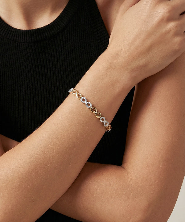 Gold bracelet on a person's wrist against a black background