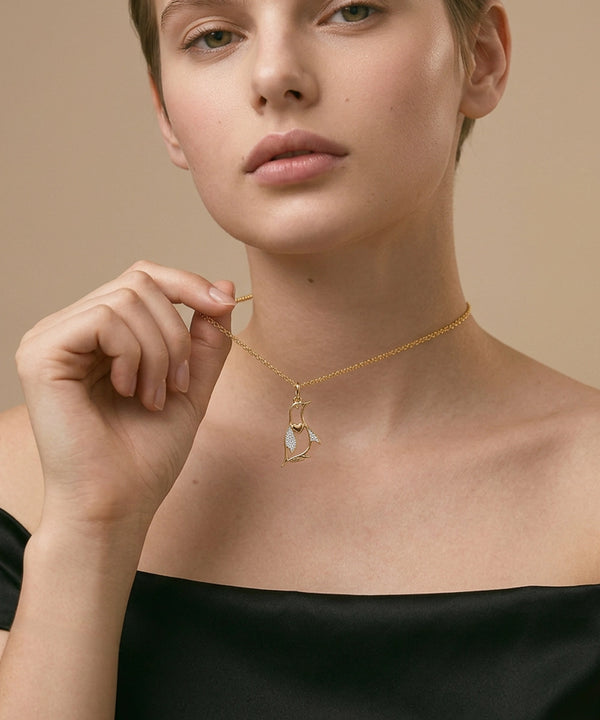 Woman wearing a gold necklace with a delicate pendant against a beige background