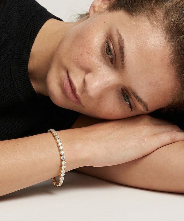 Woman wearing a diamond bracelet on a neutral background