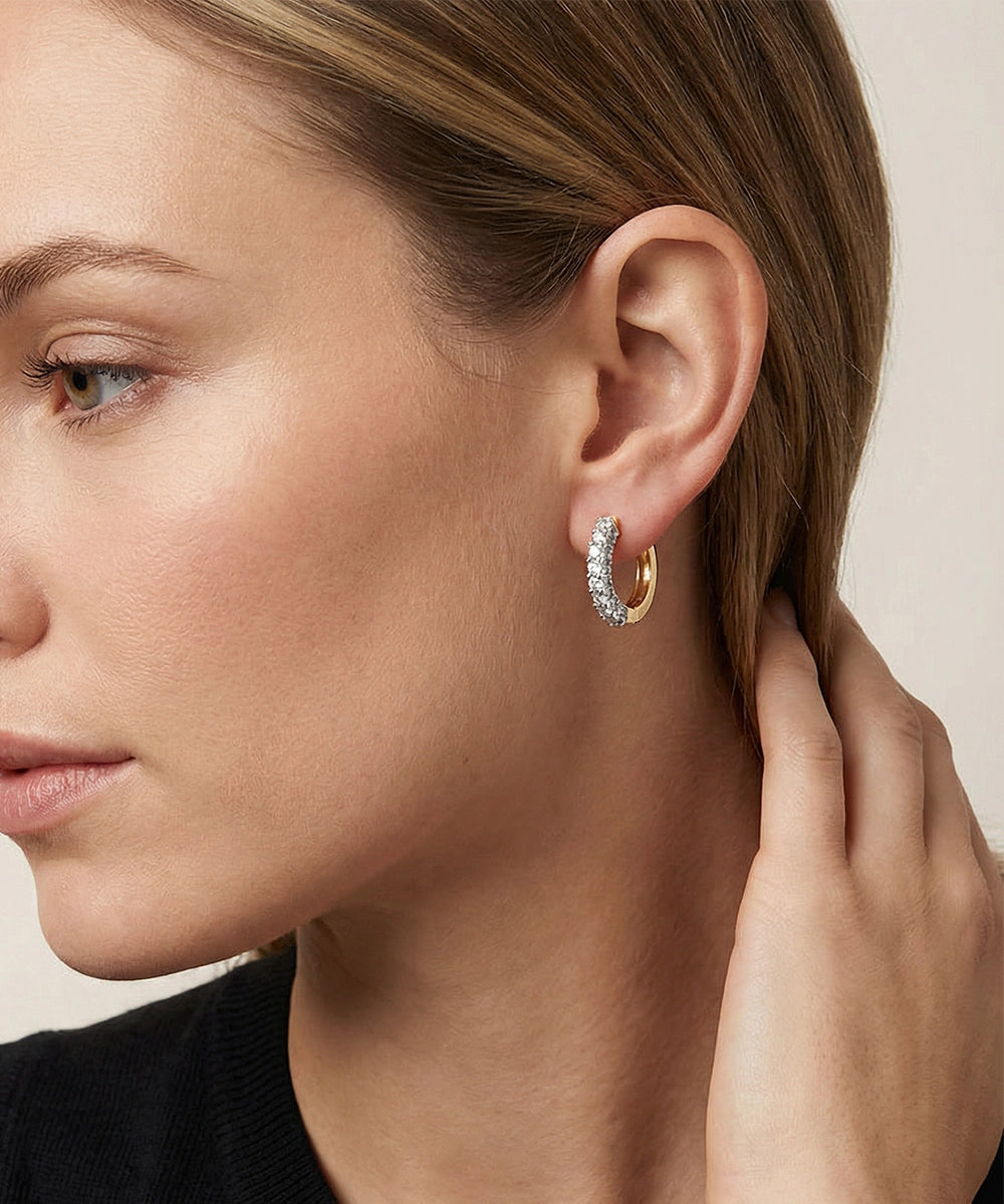 Close-up of a woman wearing gold hoop earrings with a neutral background