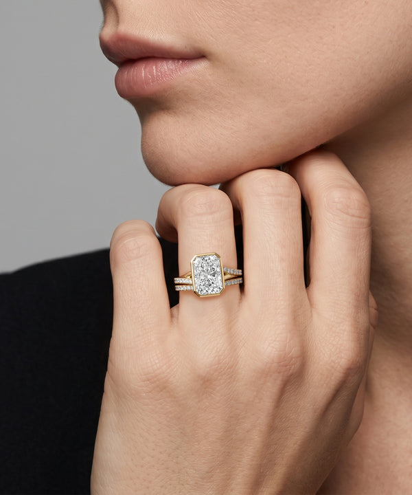 Close-up of a hand wearing a diamond ring with a neutral background