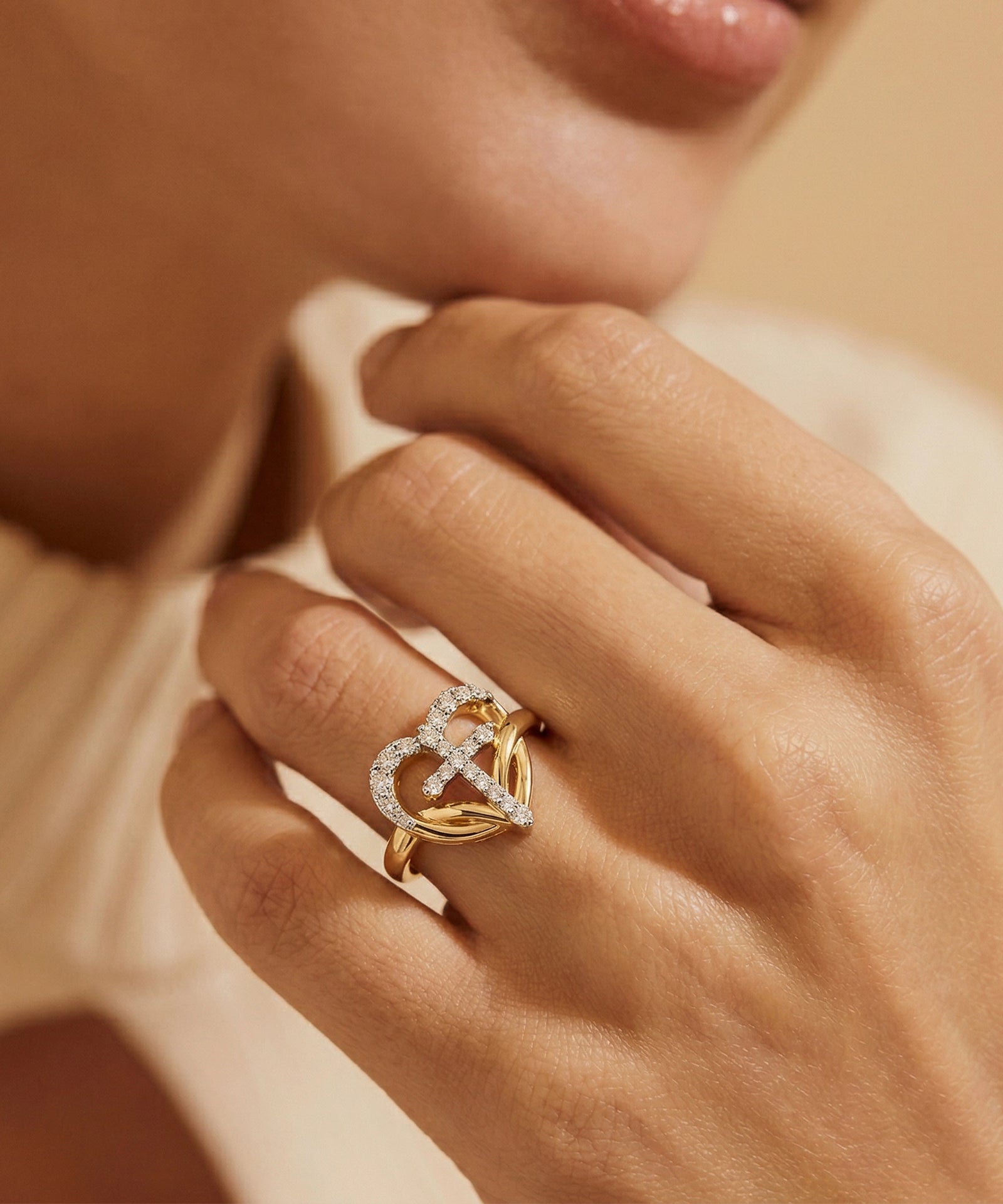 Close-up of a hand wearing a gold ring with a diamond design on a soft background