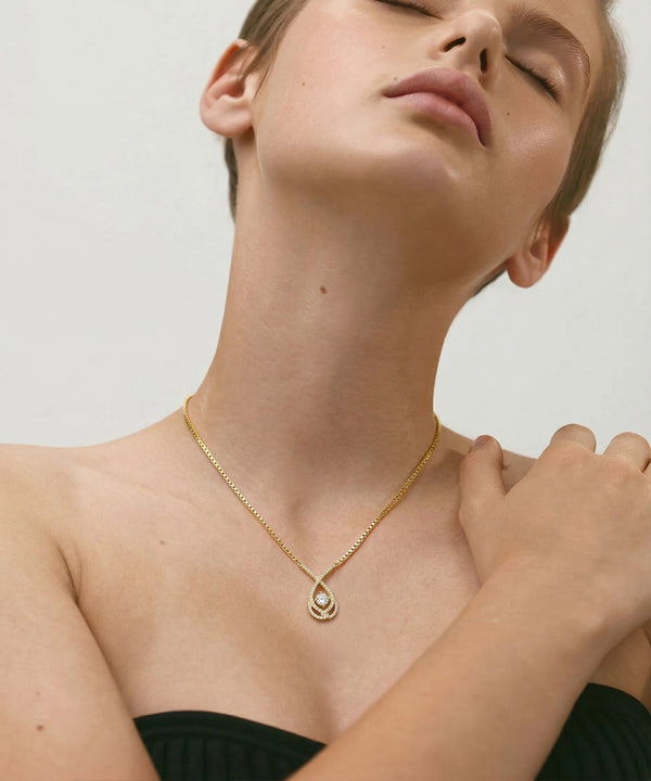 Woman wearing a delicate necklace against a neutral background