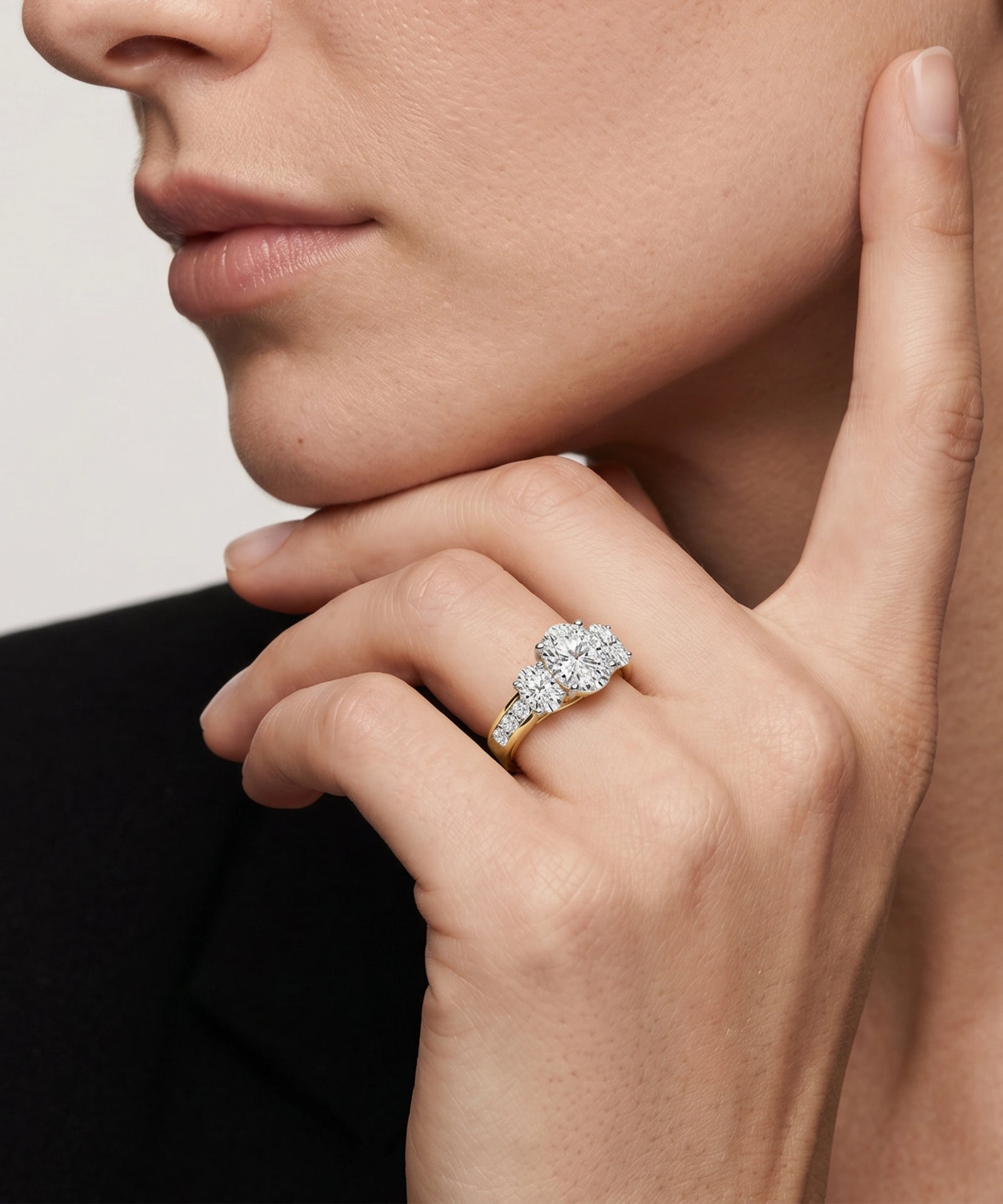 Close-up of a hand wearing a diamond ring with a neutral background