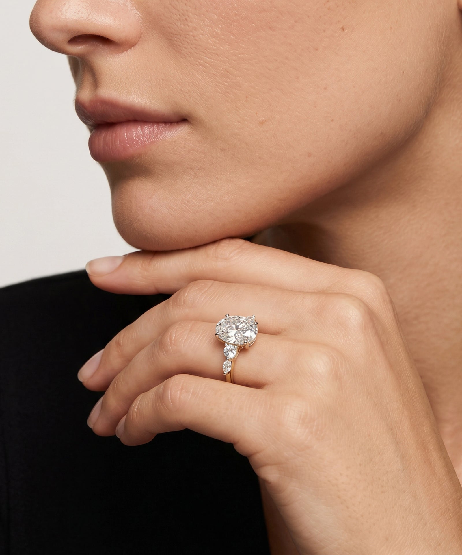 Close-up of a hand wearing a diamond ring with a neutral background