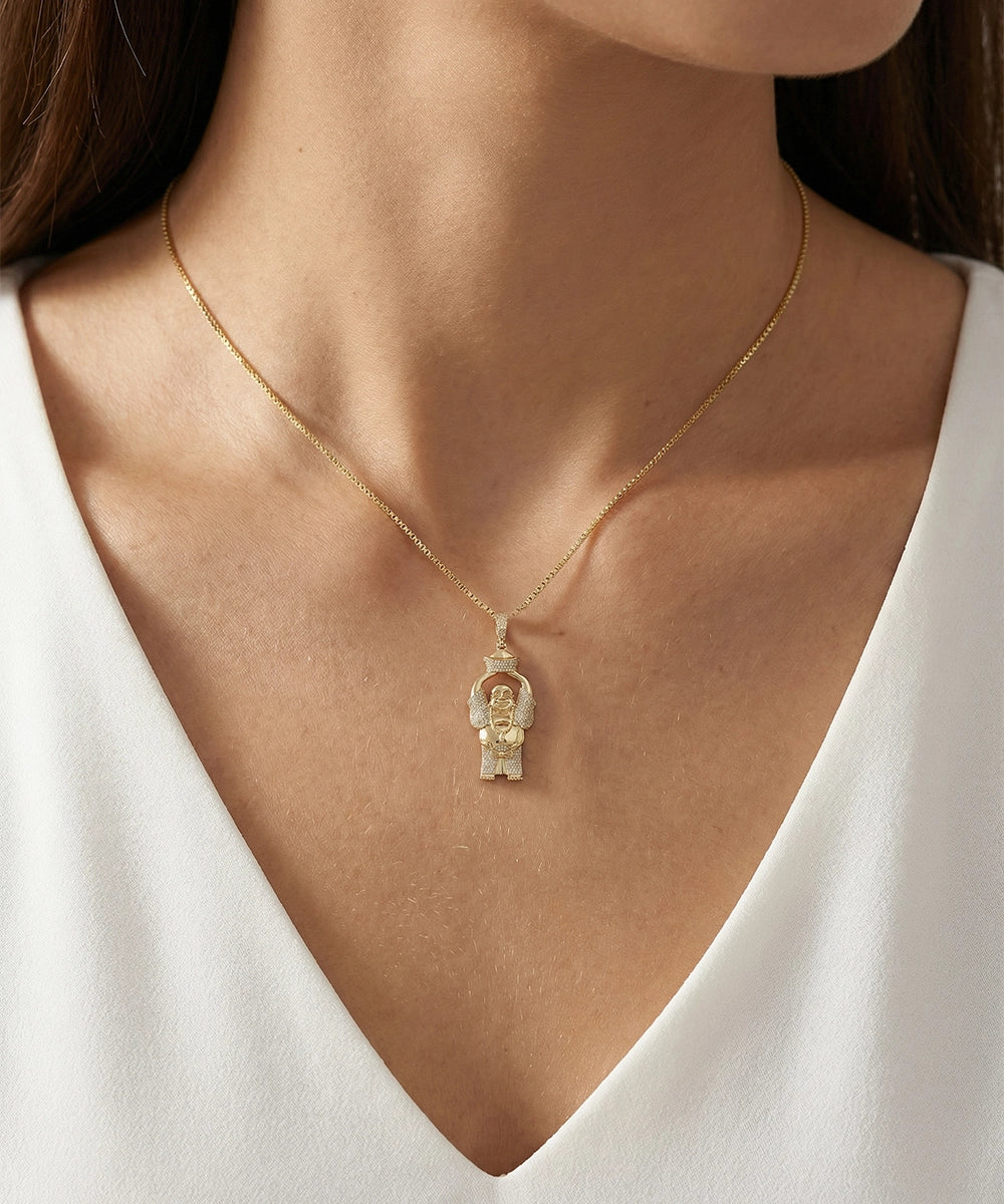 Gold necklace with a pendant on a person wearing a white top