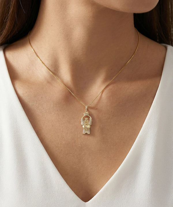 Gold necklace with a pendant on a person wearing a white top