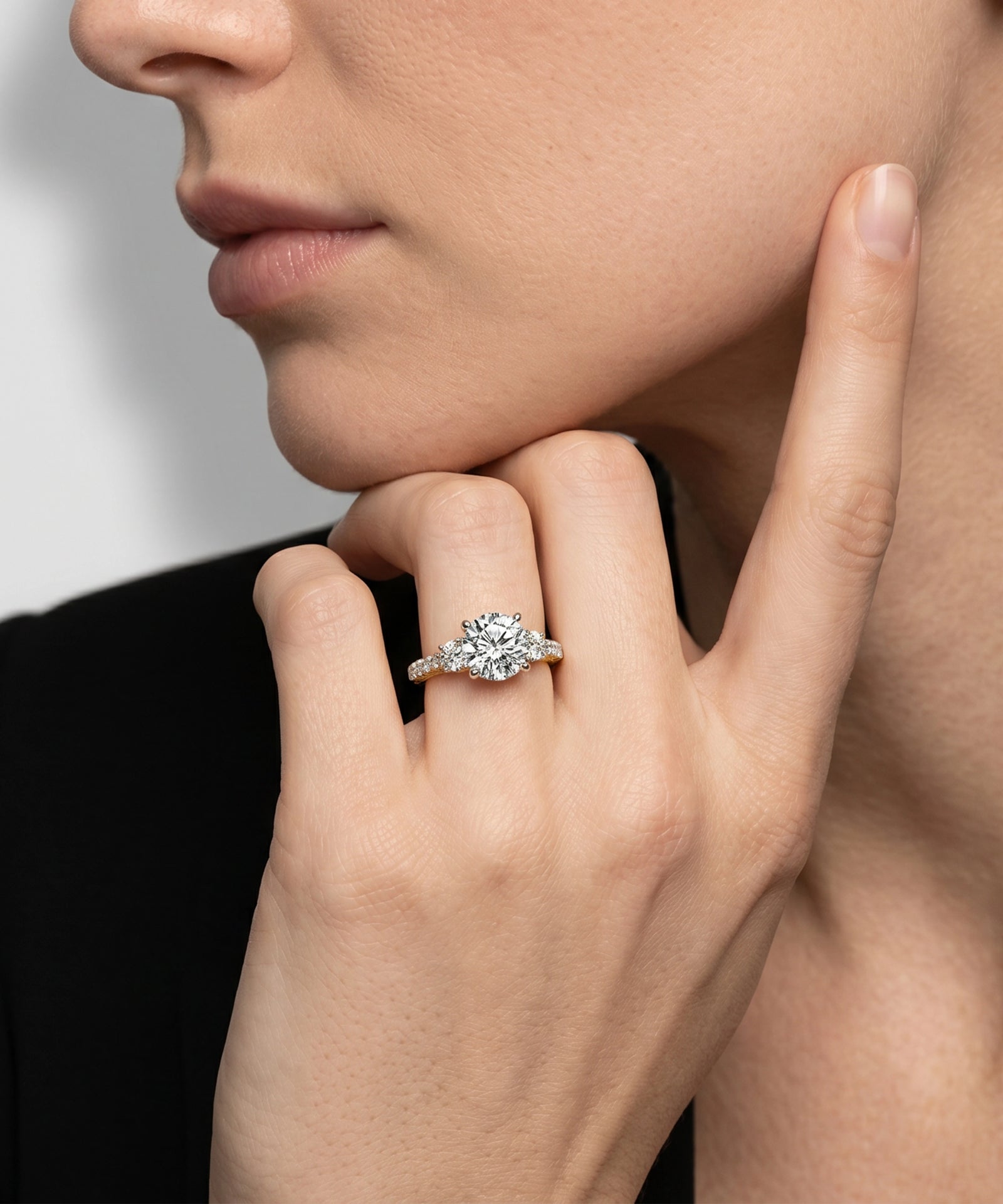 Close-up of a hand wearing a diamond ring with a neutral background
