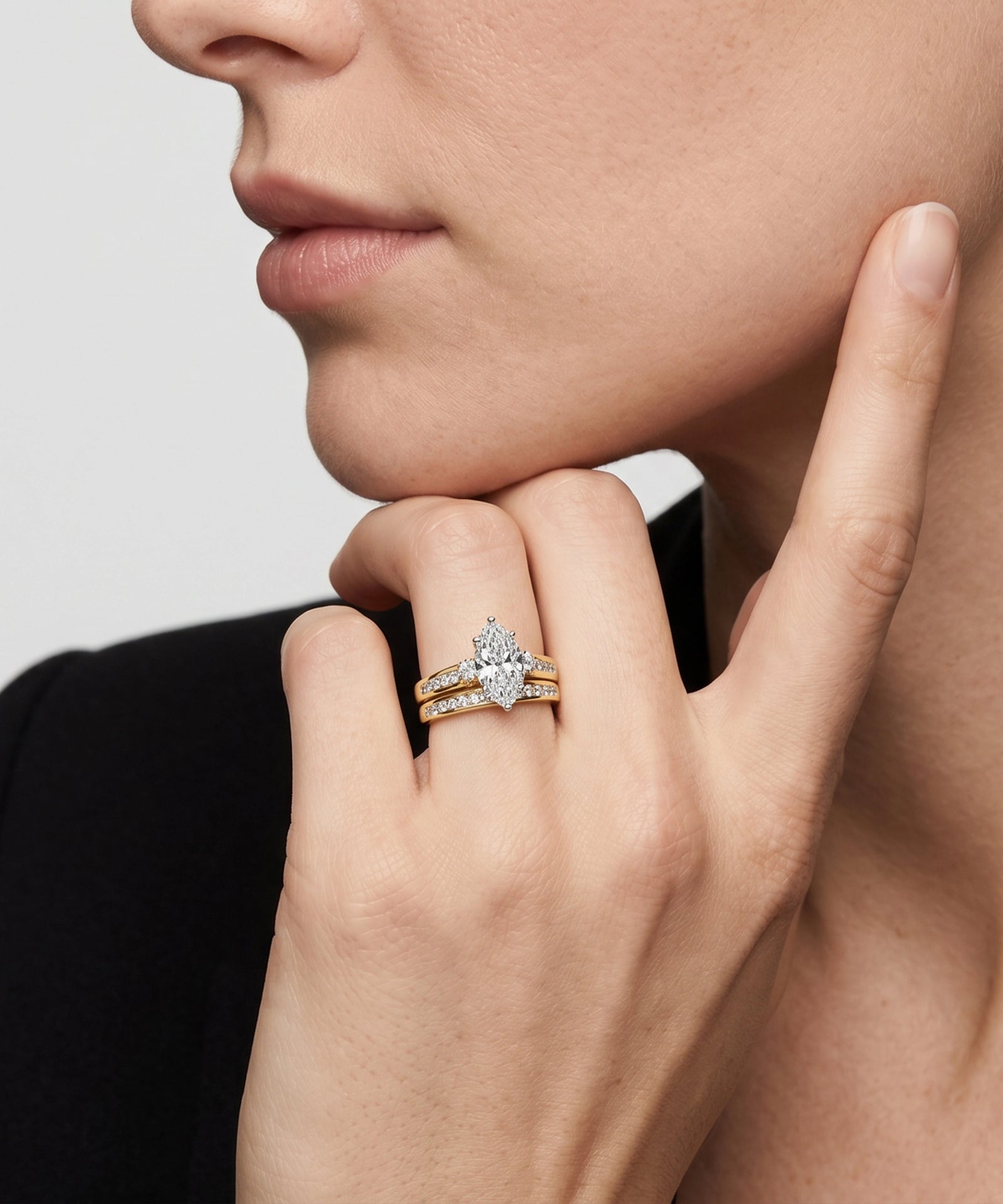 Close-up of a hand wearing a diamond ring with a neutral background