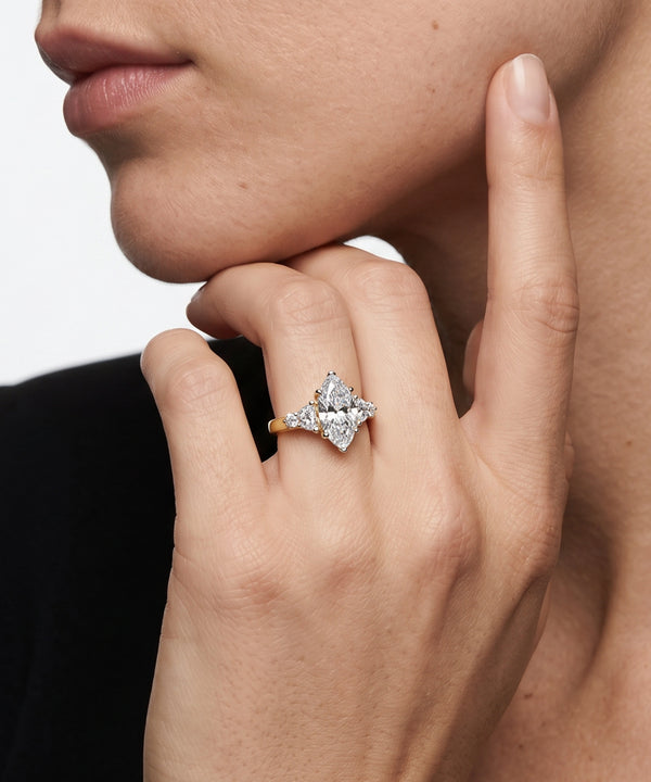 Close-up of a hand wearing a diamond ring with a neutral background