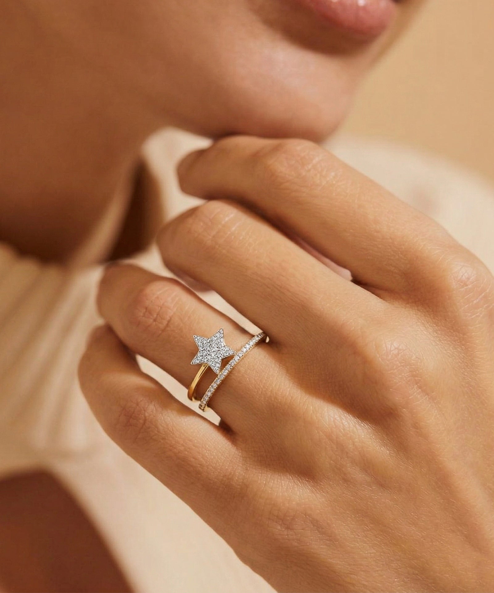 Close-up of a hand wearing a star-shaped ring on a neutral background