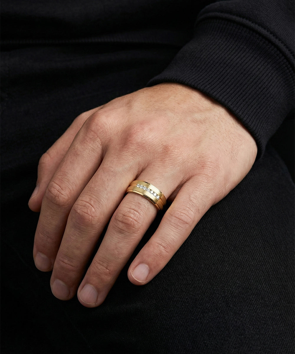 Hand wearing a gold ring on a black background