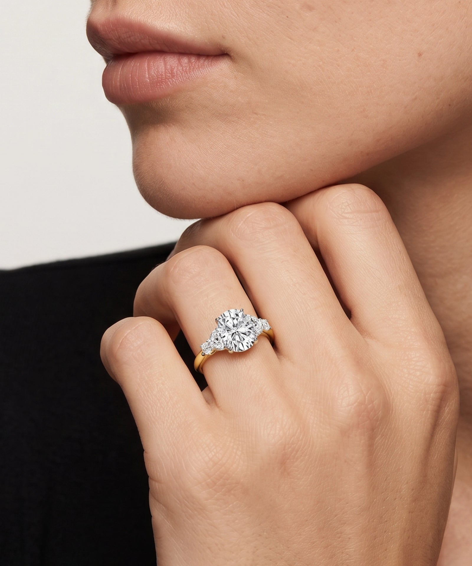 Close-up of a hand wearing a diamond ring with a neutral background