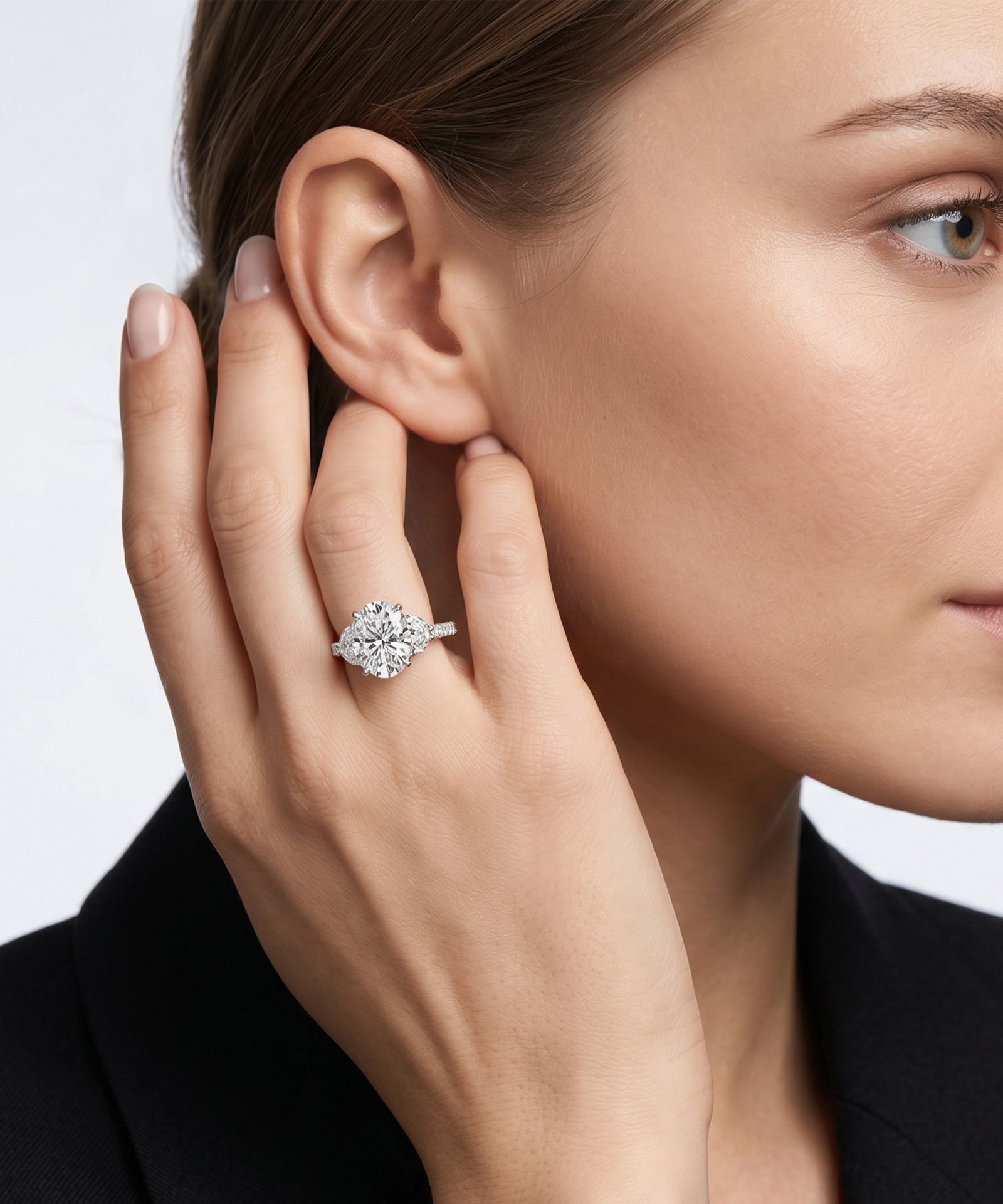Close-up of a woman wearing a diamond ring on her hand against a neutral background