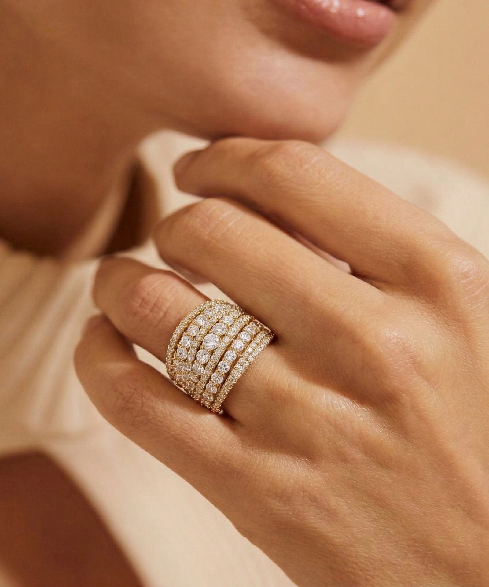 Close-up of a hand wearing multiple diamond rings on a neutral background
