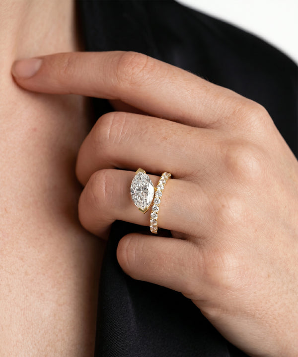 Close-up of a hand wearing two gold rings with diamond accents.