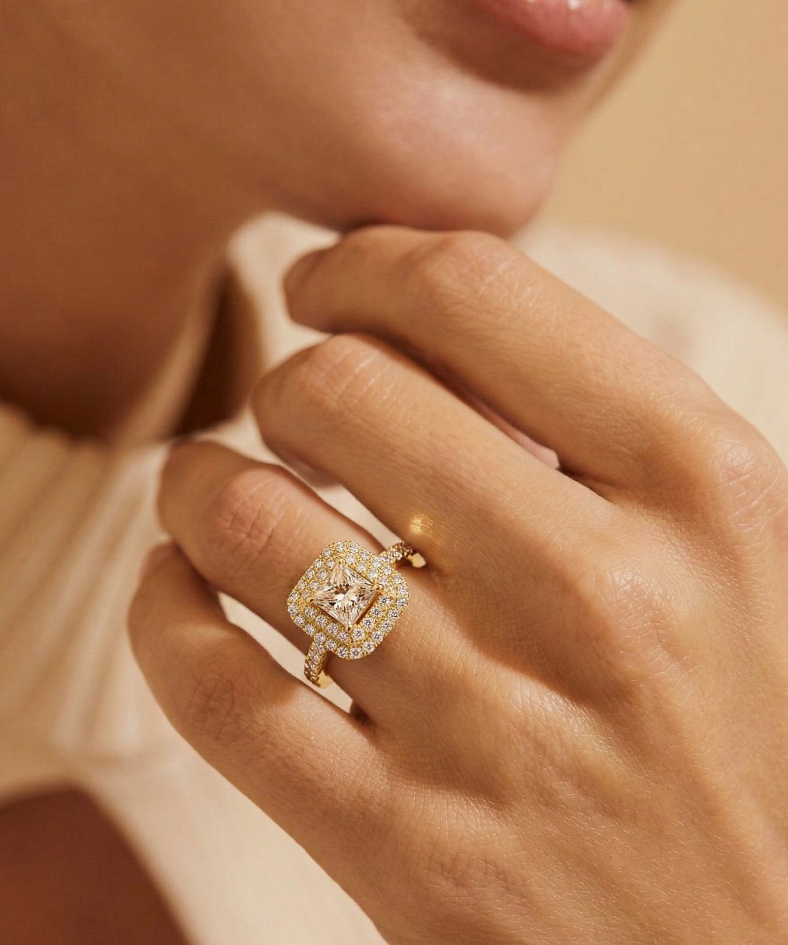 Close-up of a hand wearing a diamond ring with a soft focus background