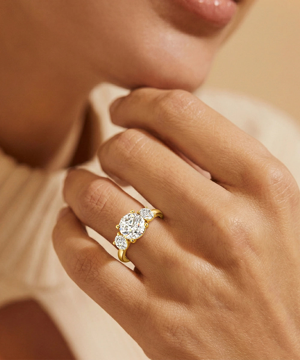 Gold ring with a diamond on a hand against a neutral background