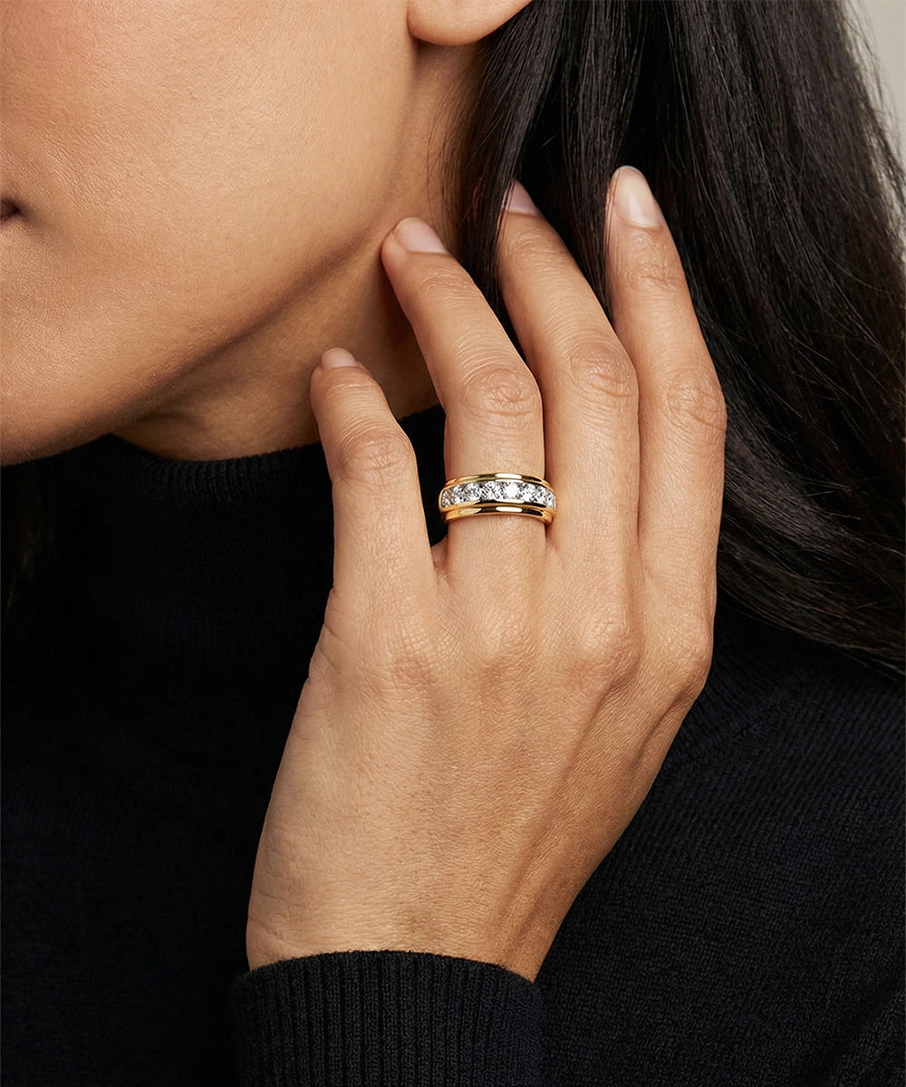 Hand wearing a gold ring with a diamond, touching the face against a neutral background
