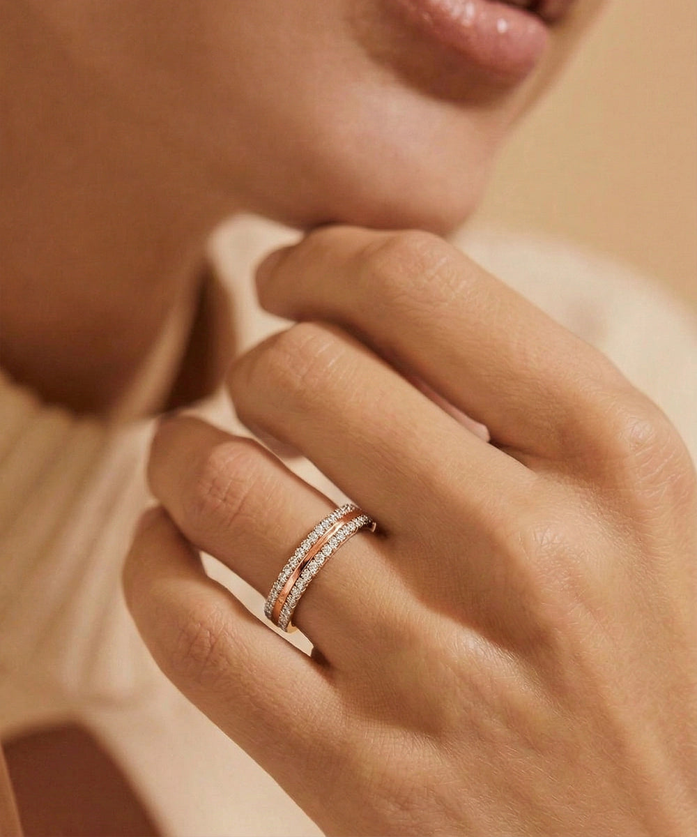 Close-up of a hand wearing a rose gold ring with diamonds on a soft background