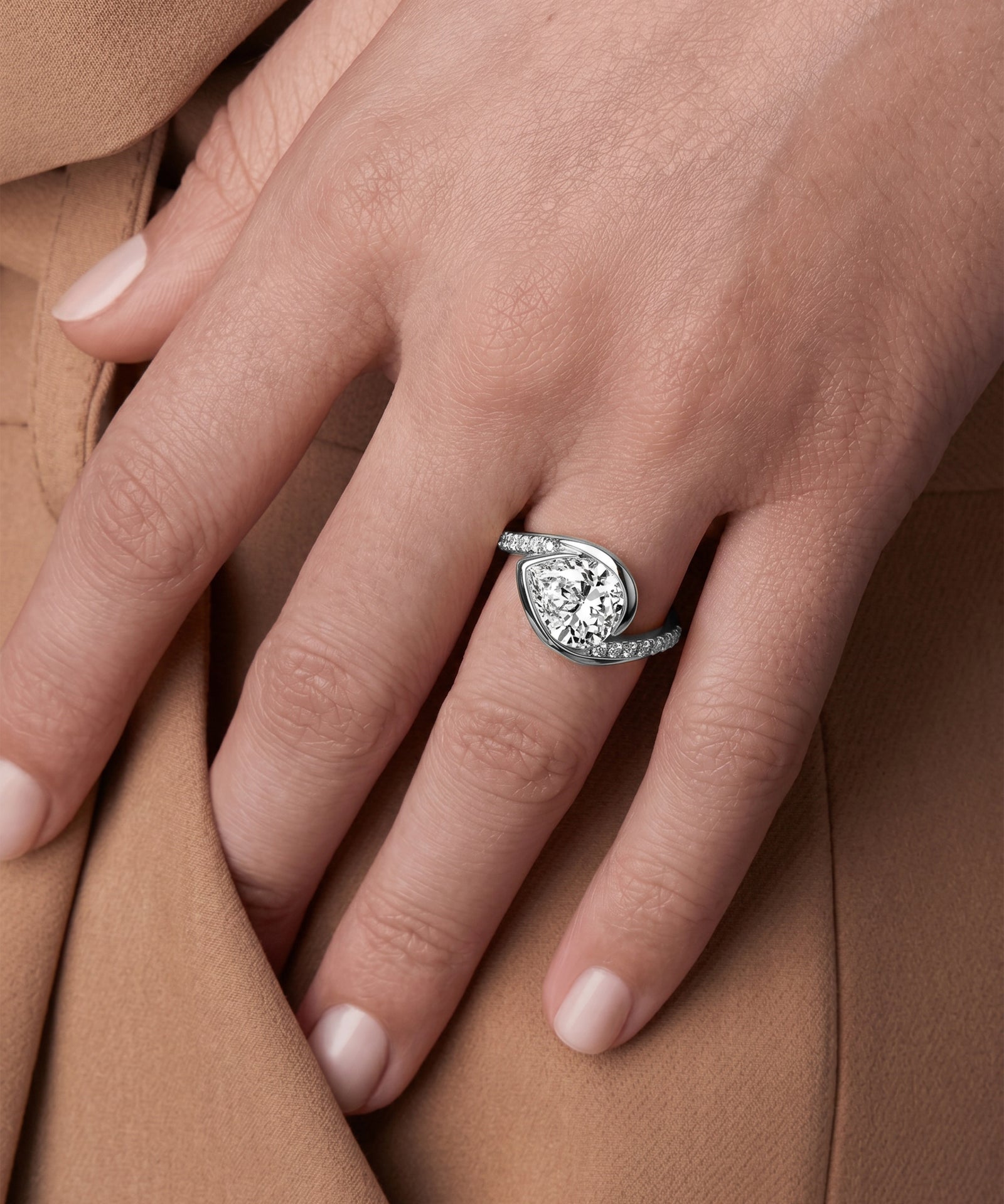 Close-up of a hand wearing a diamond ring on a brown fabric background