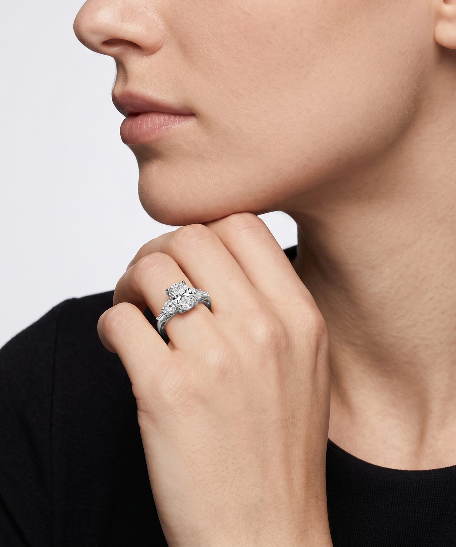 Close-up of a hand wearing a diamond ring with a neutral background