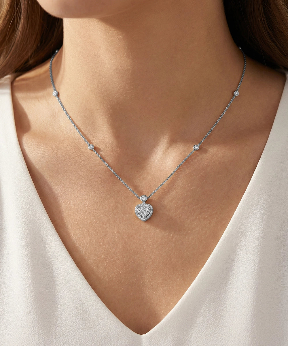 Silver necklace with a heart-shaped pendant on a person wearing a white top.
