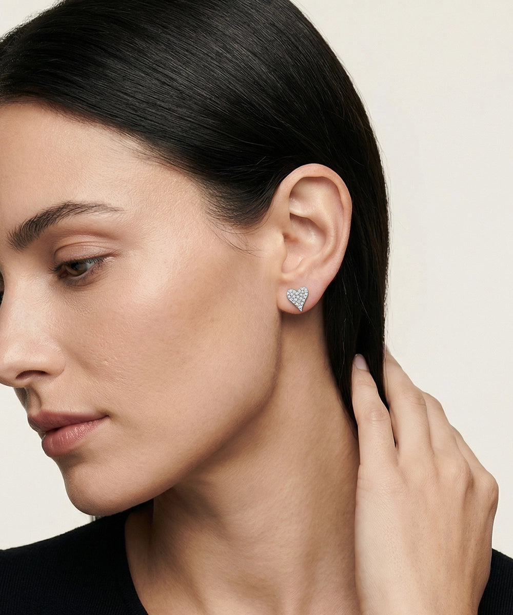 Woman wearing a heart-shaped earring on a plain background