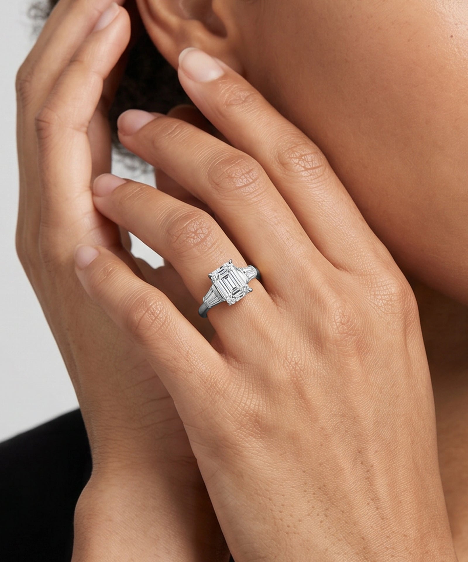 Close-up of a hand wearing a diamond ring with a white background